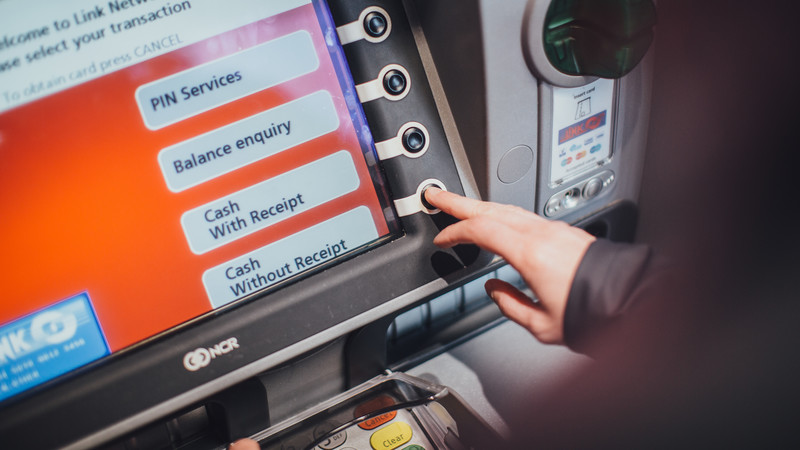 Person at a cash machine, clicking on the option for cash without receipt